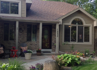 Front of two-story sage green and tan home with faux stone accents