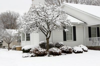 exterior shot of one-story while sided house surrounded by snow